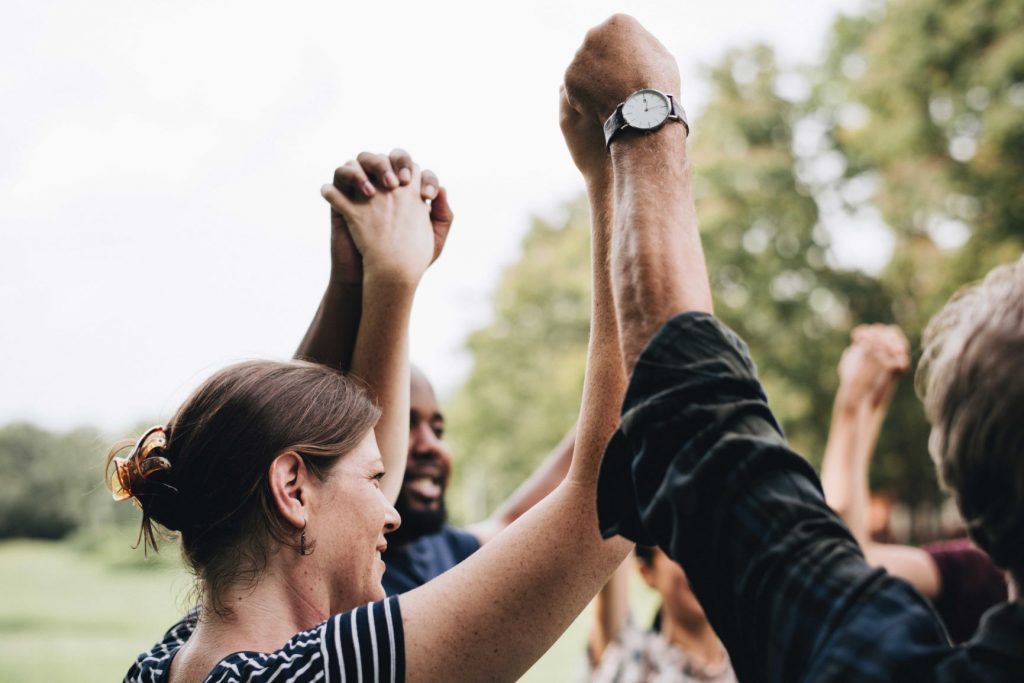 Photograph of people joining arms in the air