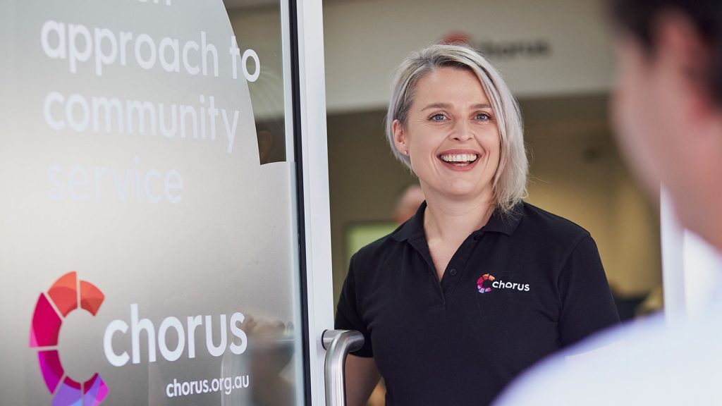 Photograph of happy Chorus staff welcoming someone inside the door