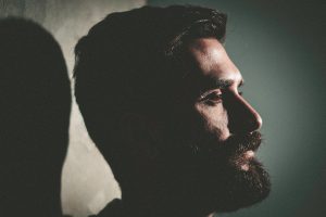 A bearded man looking quiet and withdrawn, symbolising a change in behaviour which might indicate he’s living with a mental health condition.