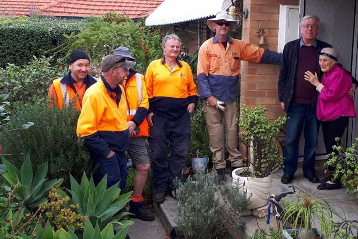 Chorus aged care volunteers gather outside the home of a couple